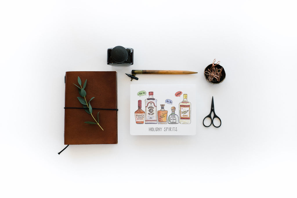 Brown leather notebook, inkwell, scissors, and greeting card on a white surface
