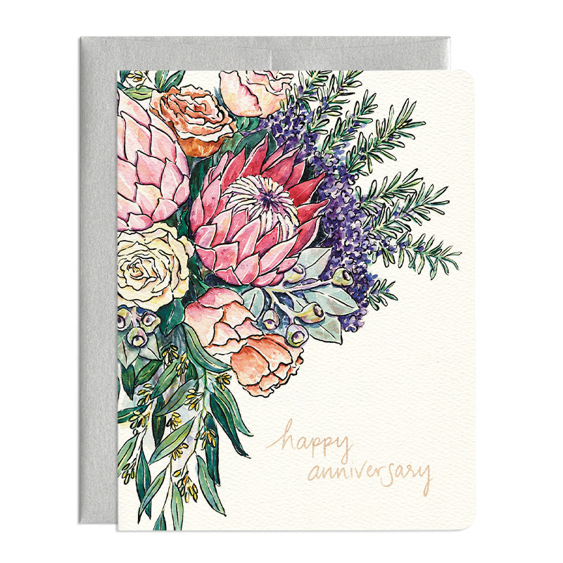 A white greeting card with a watercolour illustration of a protea flower bouquet. The card reads 'Happy Anniversary' in rose gold foil. There is a silver envelope in the background.