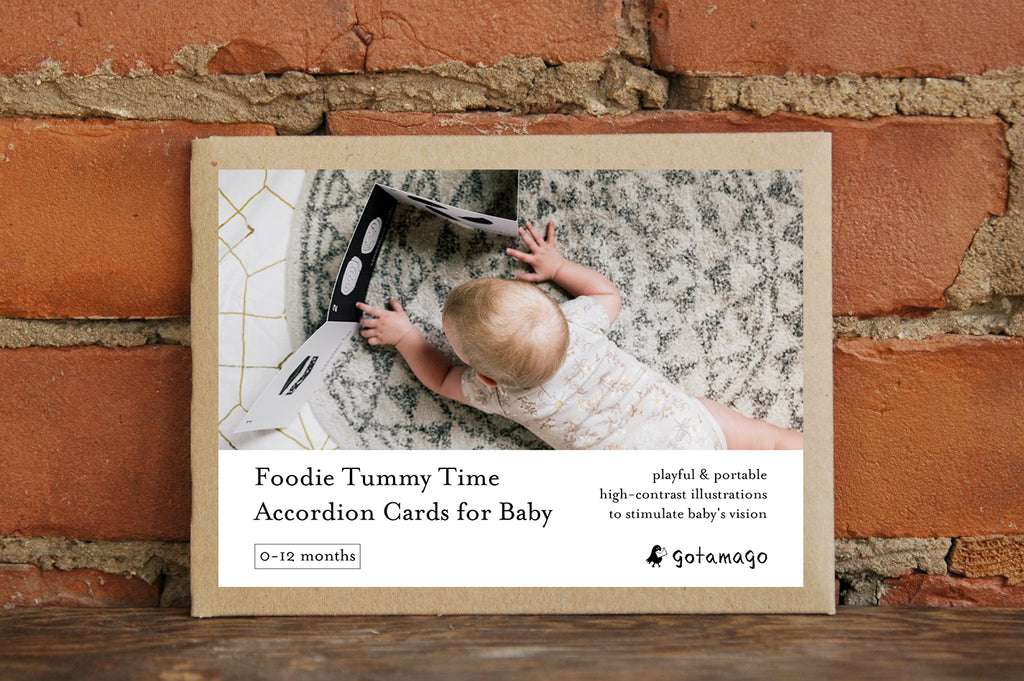 Accordian card for baby with a child on a marble rug, framed against a brick wall.