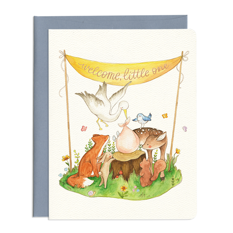 Card front features forest animals (deer, fox, bluebird, squirrel, bunny) around a stork bringing a bundled baby. Foiled, hand lettered text reads: welcome, little one.