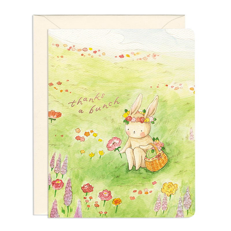Card cover features a white bunny wearing a multicoloured crown of flowers and holding a single red flower in a green field. Text in gold foil reads: thanks a bunch.