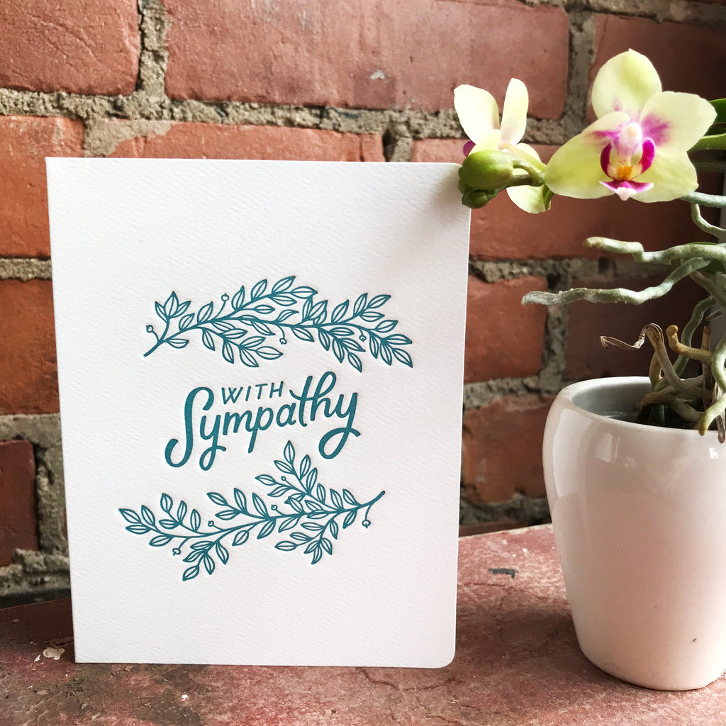 The Sympathy Leaves card stands in front of a brick wall.