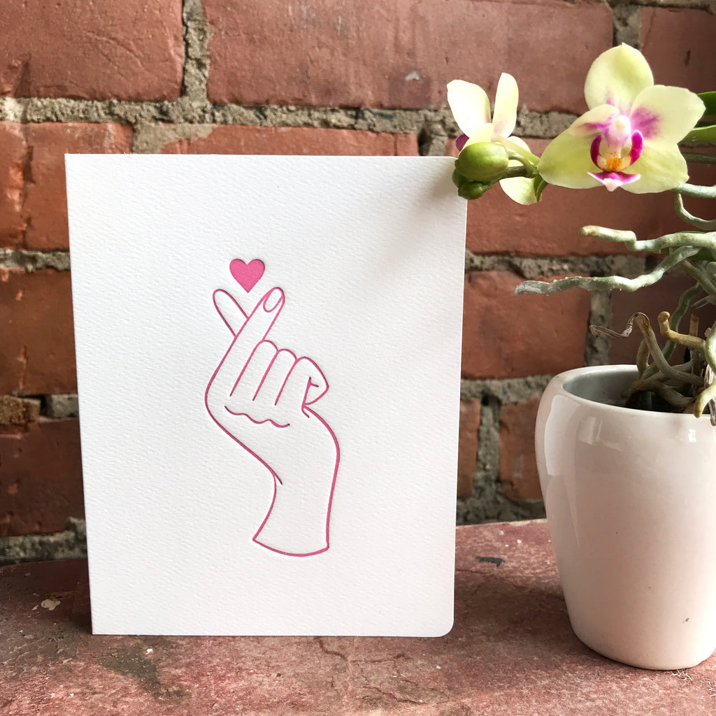 The Fingerheart card sits in front of a brick wall.